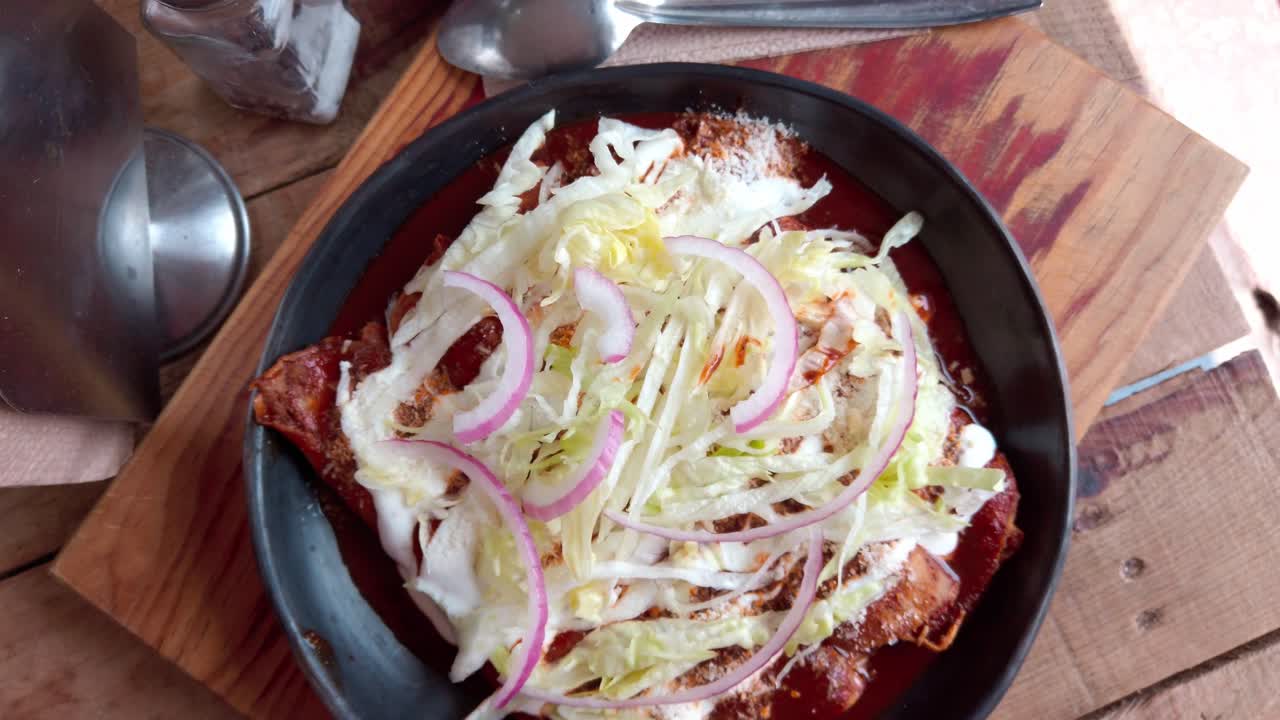 Delicious enchiladas covered with sauce, topped with shredded cabbage and onions