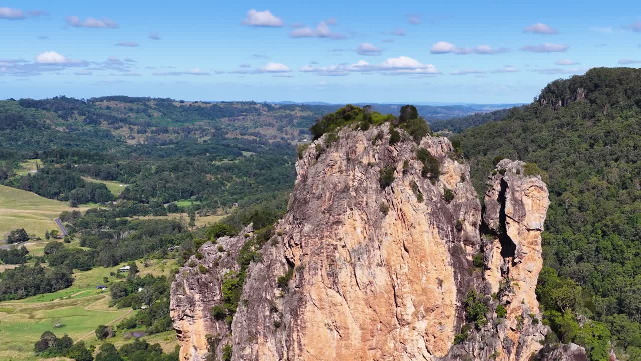 Drone footage captures the rugged beauty of Nimbin Rocks, showcasing dramatic cliffs and lush landscapes under clear blue skies