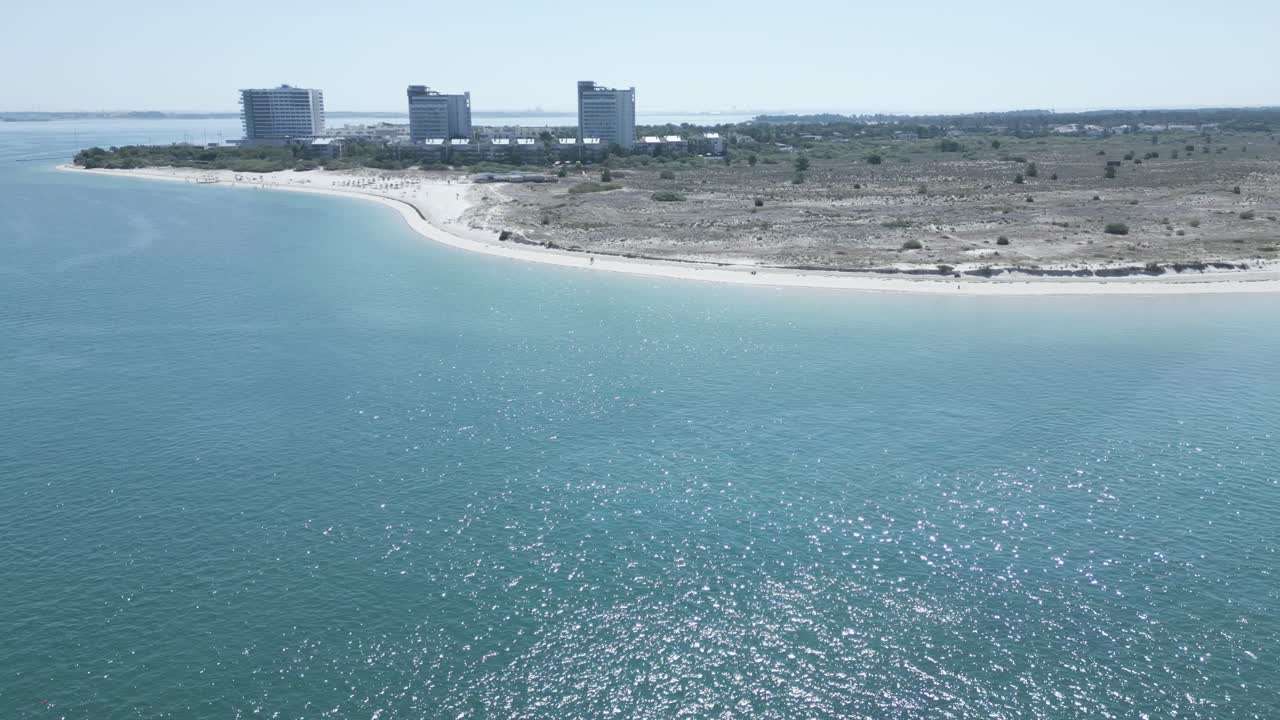 Aerial view over atlantic ocean near Troia Peninsula of Setubal, Portugal - circling, tilt, drone shot