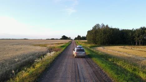 Aerial-tracking-shot-in-4k-following-a-silver-minivan-along-a-dusty-dirt-road