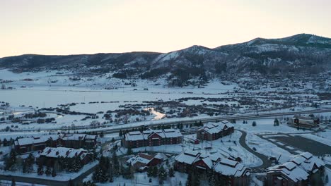 vista estática desde arriba de manantiales de vapor nevados en colorado con cabañas de esquí y resort en una puesta de sol de invierno