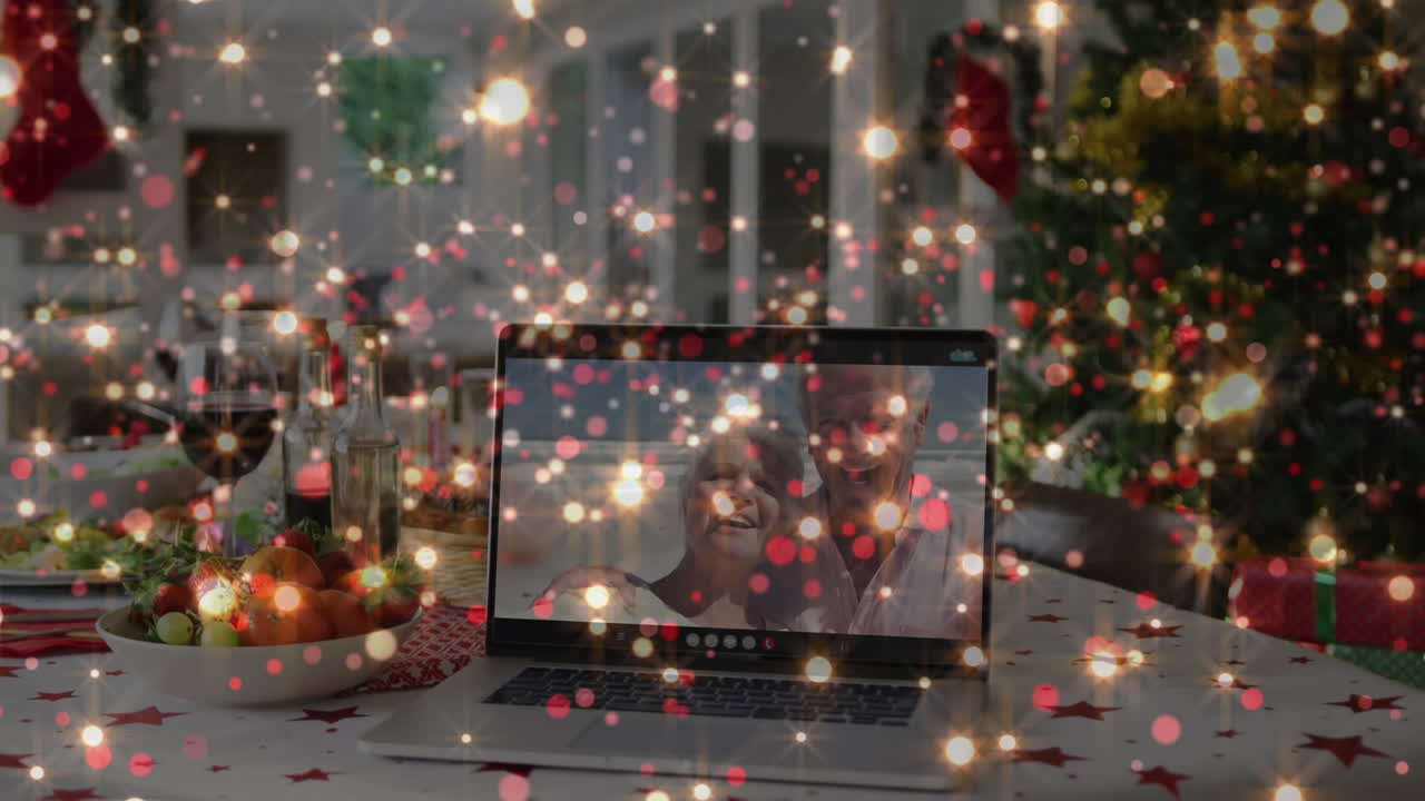 animación de luces brillantes sobre la mesa de navidad y una feliz pareja mayor en una llamada de video portátil