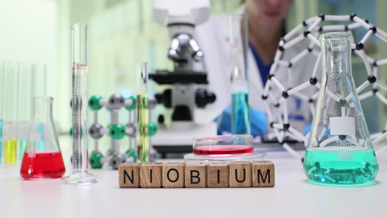 Blocchi dell'elemento Niobio su un banco da laboratorio con uno scienziato al lavoro