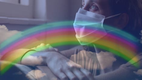 Rainbow-and-blue-sky-against-woman-wearing-face-mask