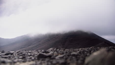 Lapso-De-Tiempo-De-Nubes-Pesadas-Grises-Que-Cubren-El-Pico-De-Montañas-Volcánicas-Rocosas-En-Fuerteventura-Isla-Canaria-España