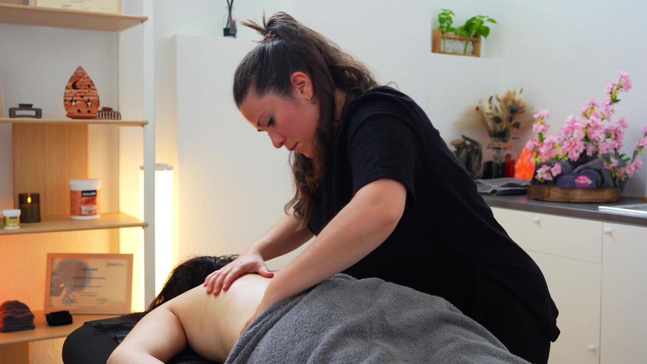 Osteopata profissional feminina massageando as costas de um cliente para alívio da dor em uma clínica de bem-estar.