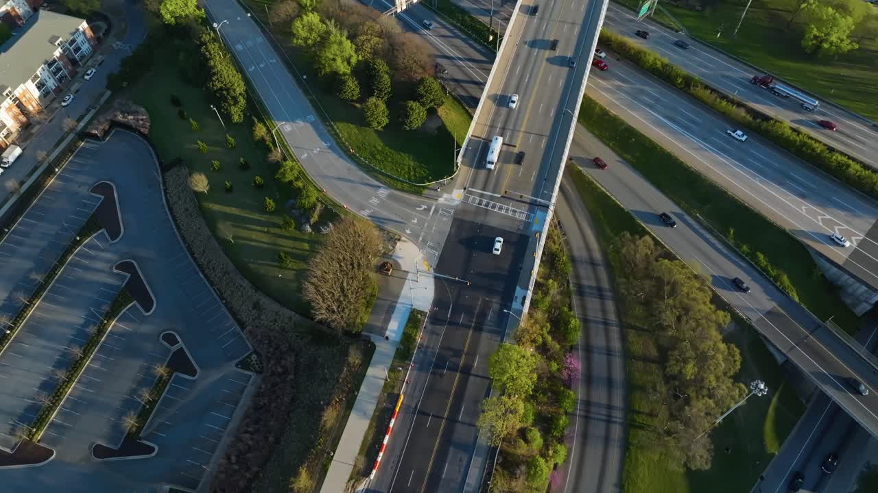 Busy traffic scene with cars and trucks on american interstate road at sunset time. Green trees and housing area with townhouses in Suburb of Atlanta, Georgia. Aerial top down circle shot.