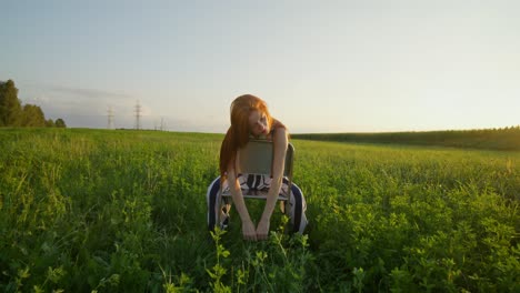 mujer sentada en una silla de metal en un campo al atardecer