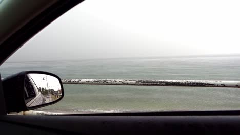 mirando al mar mediterráneo a través de una ventana de un coche por un día lluvioso