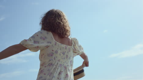 niña despreocupada bailando en la playa con vestido de flores de cerca. mujer divertirse en la naturaleza.