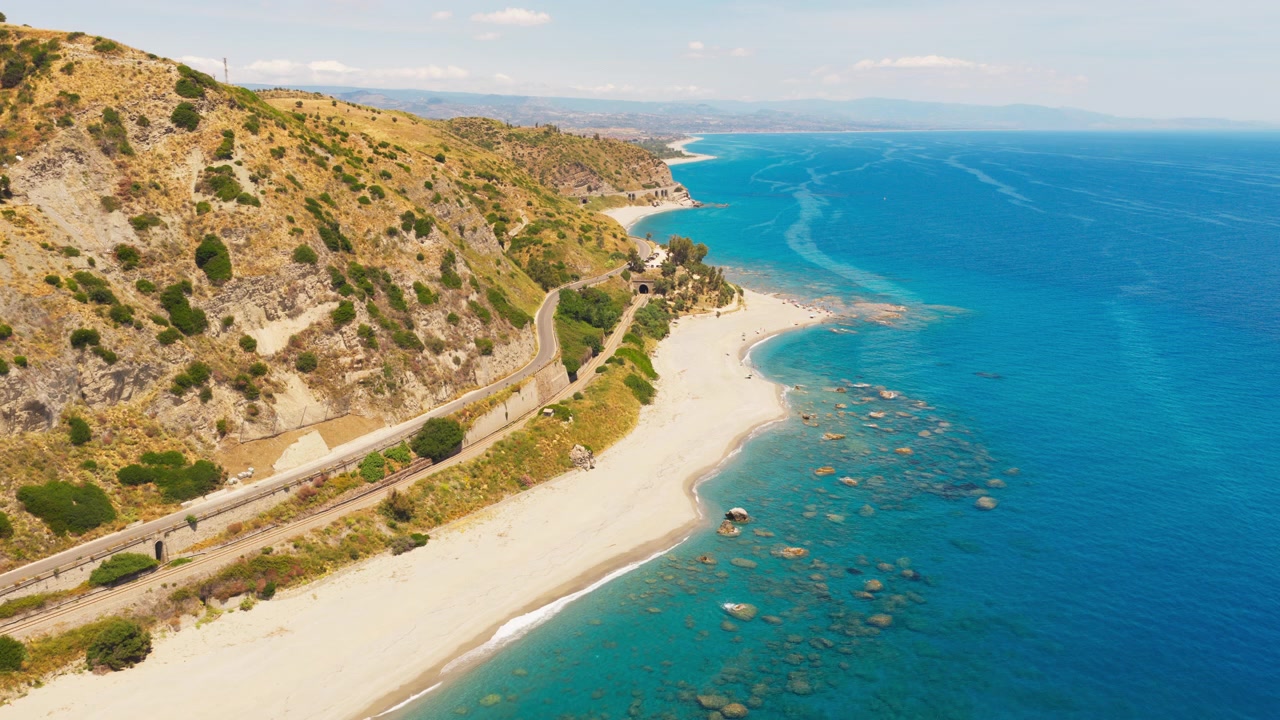Splendida vista aerea di una spiaggia sabbiosa e dell'oceano azzurro con strada costiera e ferrovia