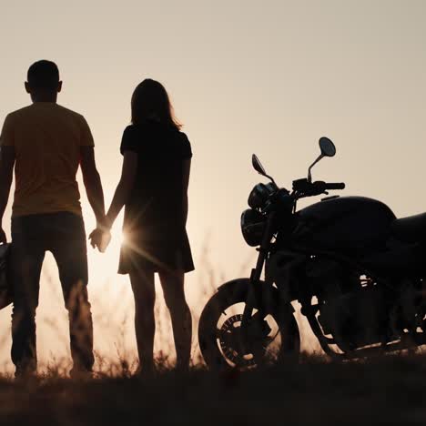 Ein-Junges-Motorradfahrerpaar-Bewundert-Den-Sonnenuntergang-über-Dem-Horizont
