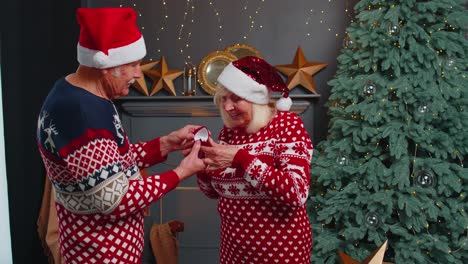 amoroso abuelo regalando regalo de navidad caja de joyas con anillo de oro a la abuela sorprendida