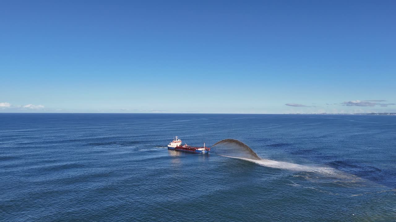 Aerial view of a dredger spraying sand into the ocean under clear skies at Gold Coast, Australia