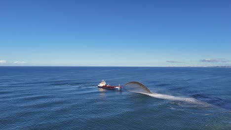 aerial view of a dredger spraying sand into the ocean under clear skies at gold coast, australia