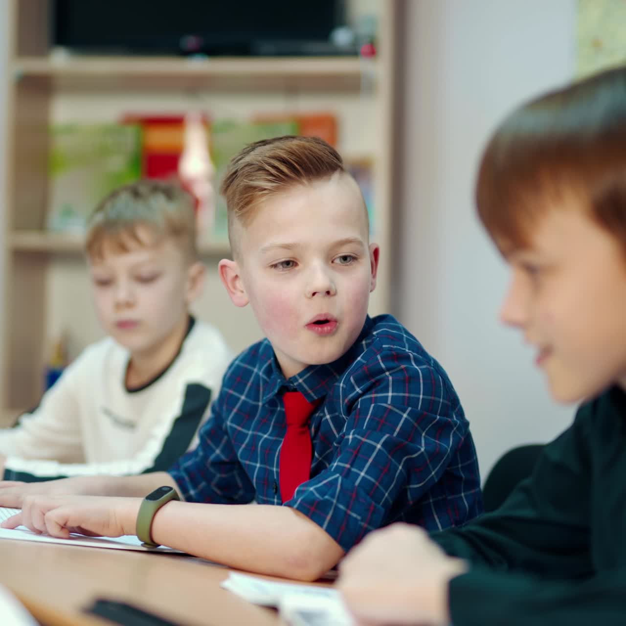 Back to school. Little boys studying at school. Group of smiling kids sitting at the table and talking. Education concept.