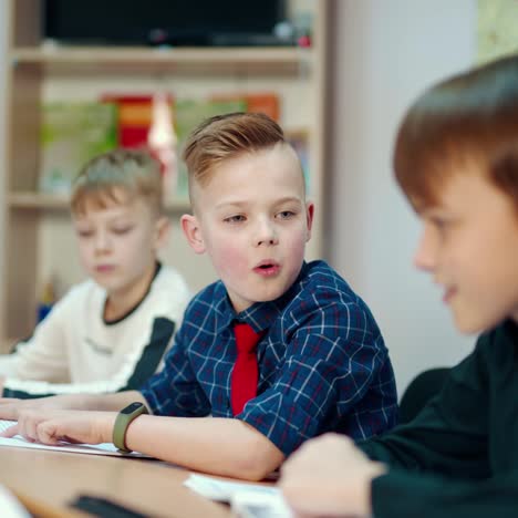 back to school. little boys studying at school. group of smiling kids sitting at the table and talking. education concept.
