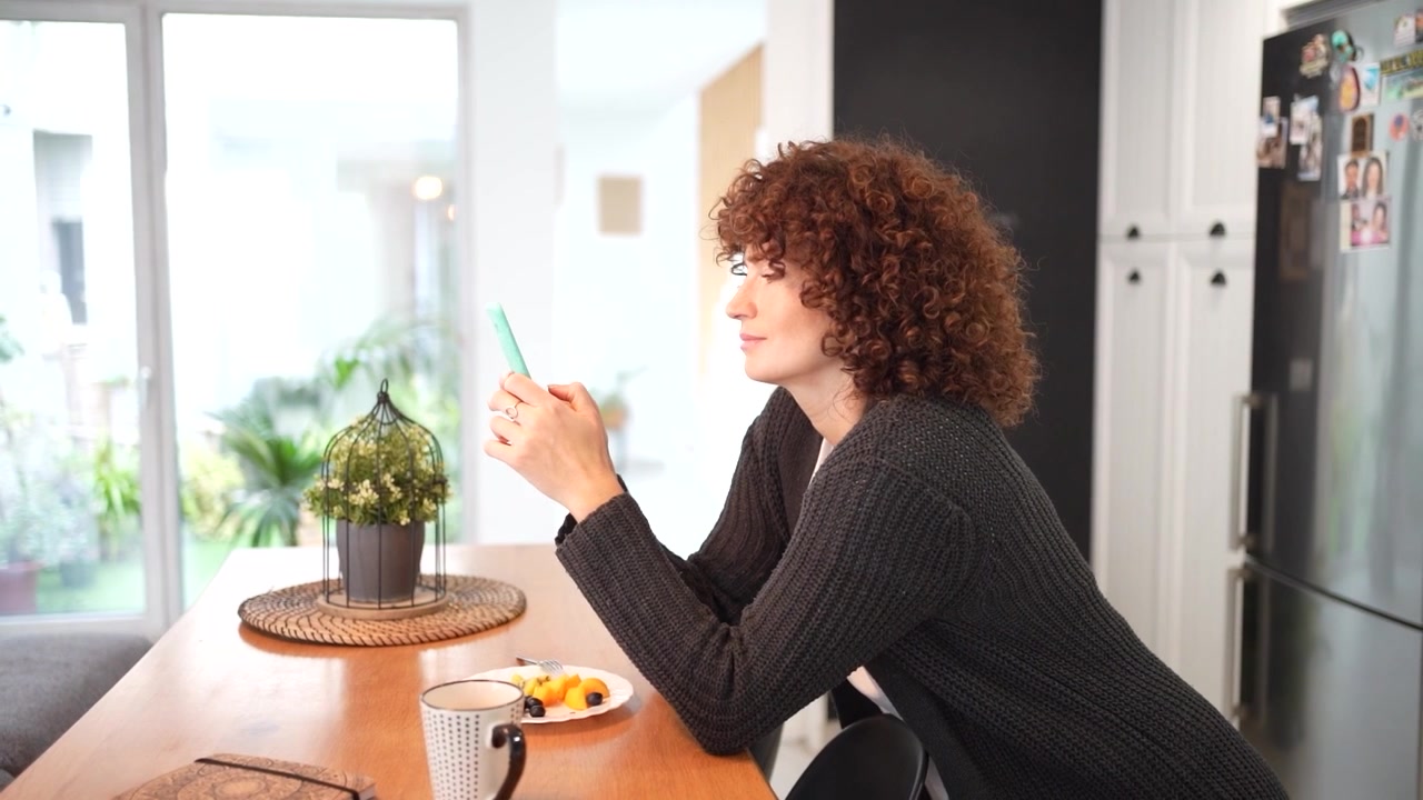 A woman delightfully enjoying a warm morning coffee and a light breakfast in a cozy kitchen