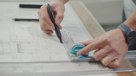 architect's desk: drawings tape measure ruler and other drawing tools. engineer works with drawings in a bright office close-up. insturments and office for designer. male hands draw with a pencil.