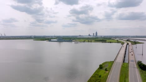 Wide-view-of-USS-Alabama-battleship-with-skyline-of-Mobile,-Alabama-with-drone-video-moving-in