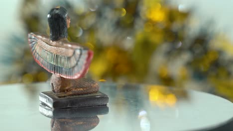 dreamy close-up shot of a cleopatra statue with wide open wings, hazy golden depth of field, ancient, egyptian historical ruler, antique artwork of a goddess, rotating 360 slow 4k video pan right