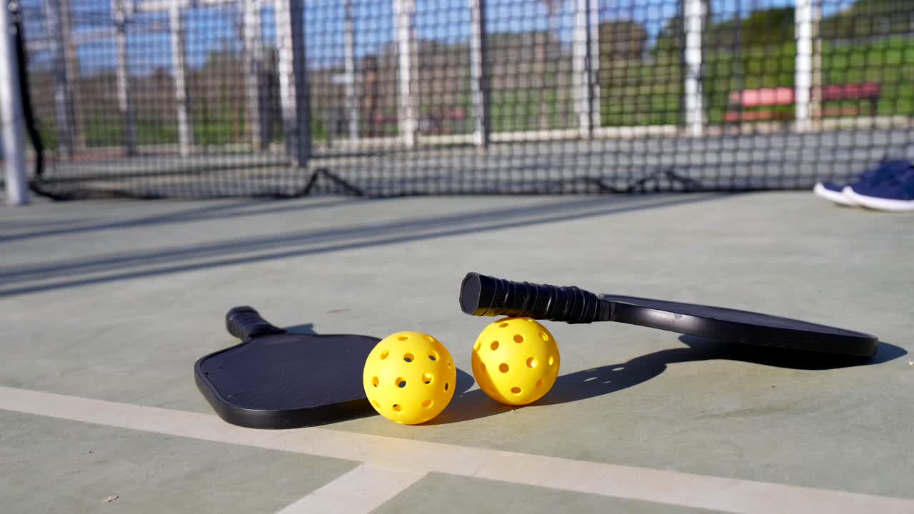 Pickleballracketer og baller på en utendørsbane