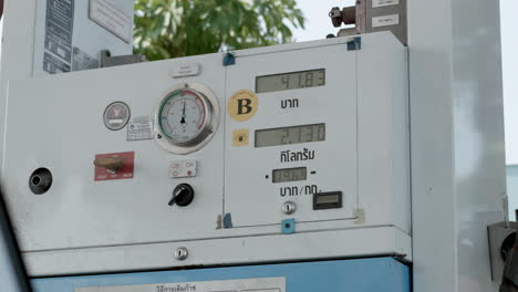 numbers for amount of liters and price equivalent in baht are displayed on a gauge machine at a refuelling station in bangkok, thailand