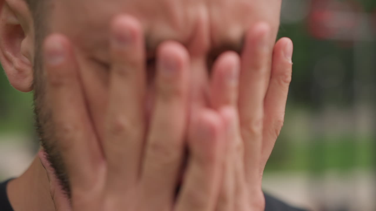 Focused Man Pauses Workout Mentally, Man Exhibits Tense Expression While Transitioning Between Workout Sets, Closeup Of Man Showing Concentrated Expression During Physical Activity Break In Park
