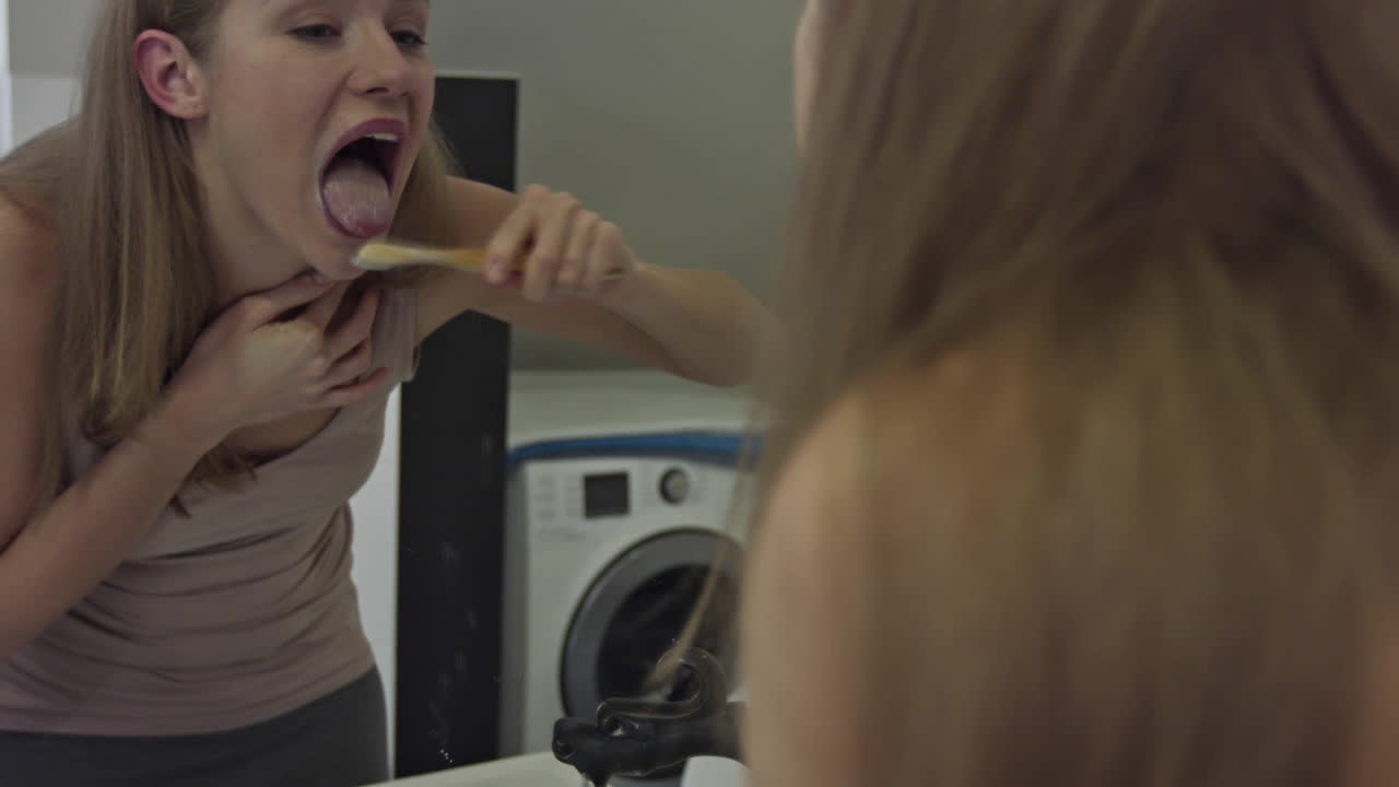 A woman washes her tongue with a bamboo toothbrush