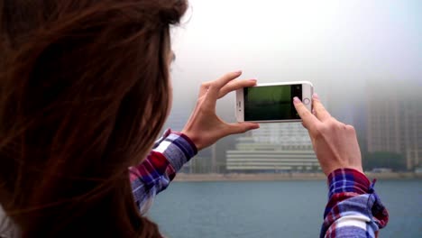 Mobile-phone-in-hands-making-foto-city-fog.-Concept-of-mobile-photography