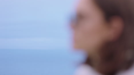 portrait of beautiful caucasian woman wearing sunglasses enjoying peaceful seaside at sunset looking contemplative running hand through hair