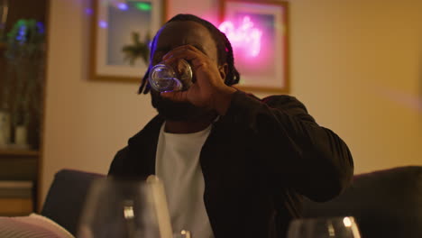 man sitting on sofa after drinking alcohol at house party drinking glass of water for hangover 3