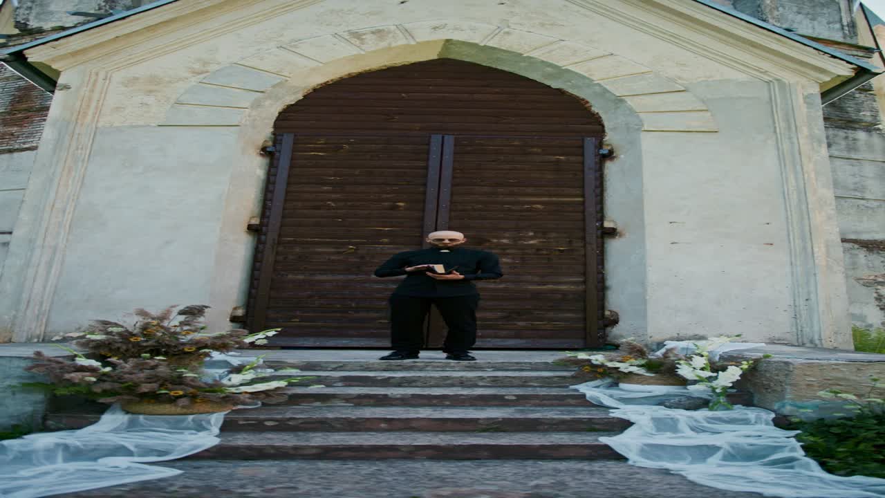 Priest Standing in Front of Church Doors