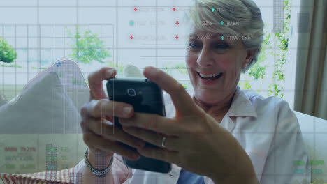 holding smartphone and smiling, woman with stock market data animation over