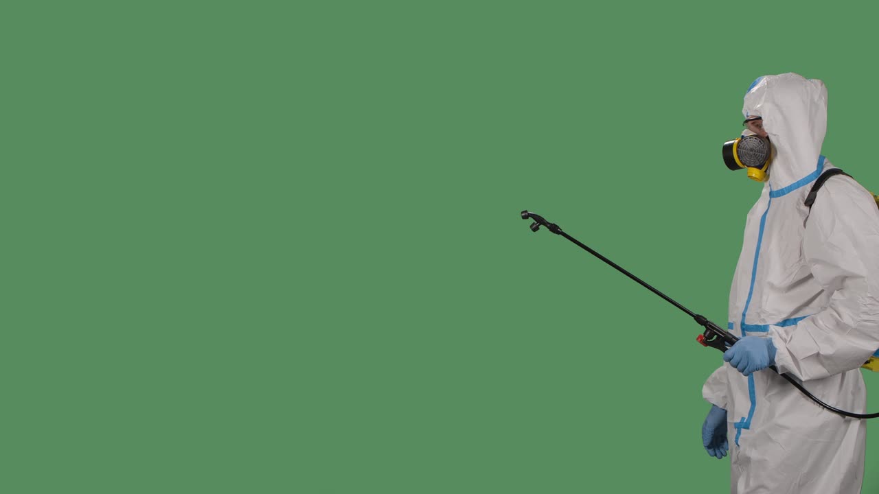 vista lateral hombre en un traje de protección con una lavadora a presión desinfecta el área infectada con spray antiséptico en una pantalla verde, llave de croma. cerca. cámara lenta