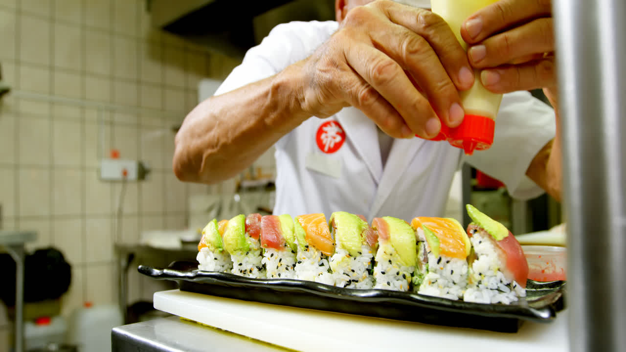 chef masculino cubriendo la salsa en el sushi en la cocina 4k