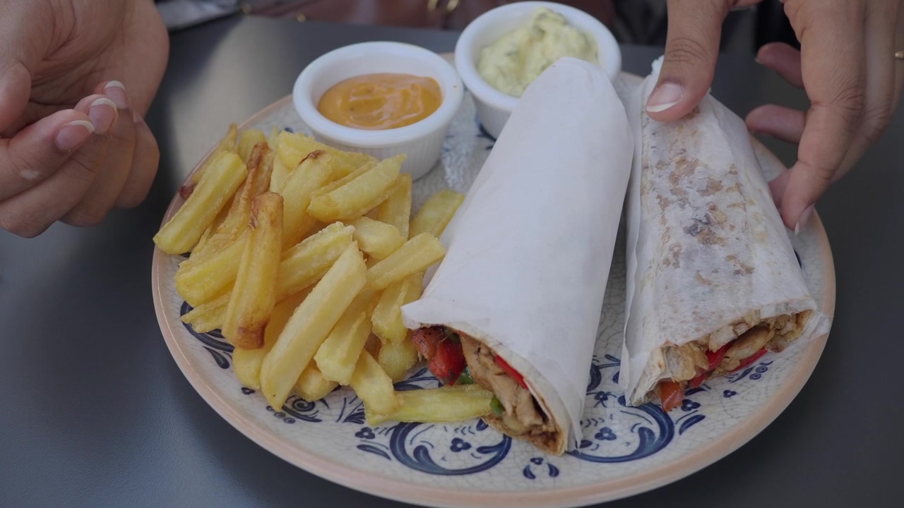 Person Picking Up a Chicken Wrap with French Fries