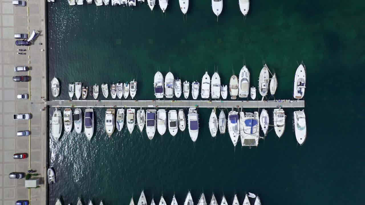 A marina in sardinia with various boats docked along a pier, aerial view