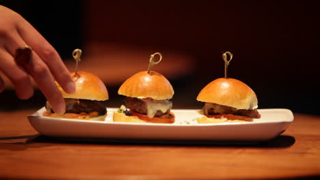 a tray of delicious beef sliders is served at a restaurant as a customer grabs a slider to eat