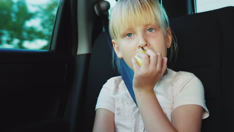 snack on the road the girl eats an apple rides in the back seat of the car 4k video