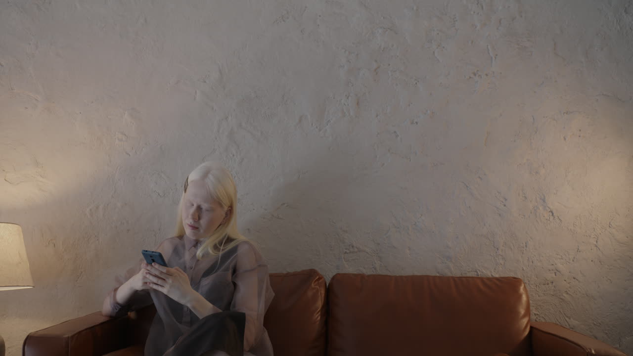 소파에서 스마트폰을 사용하는 여성