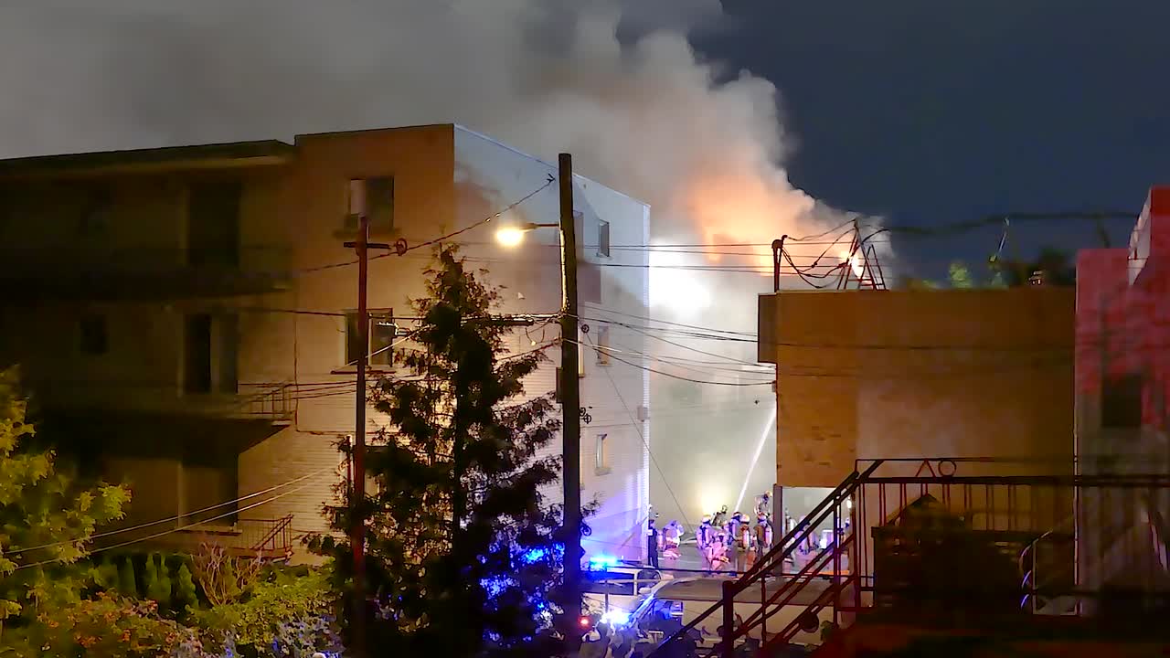 Firefighters Battle Blaze at Night in City Apartment Building