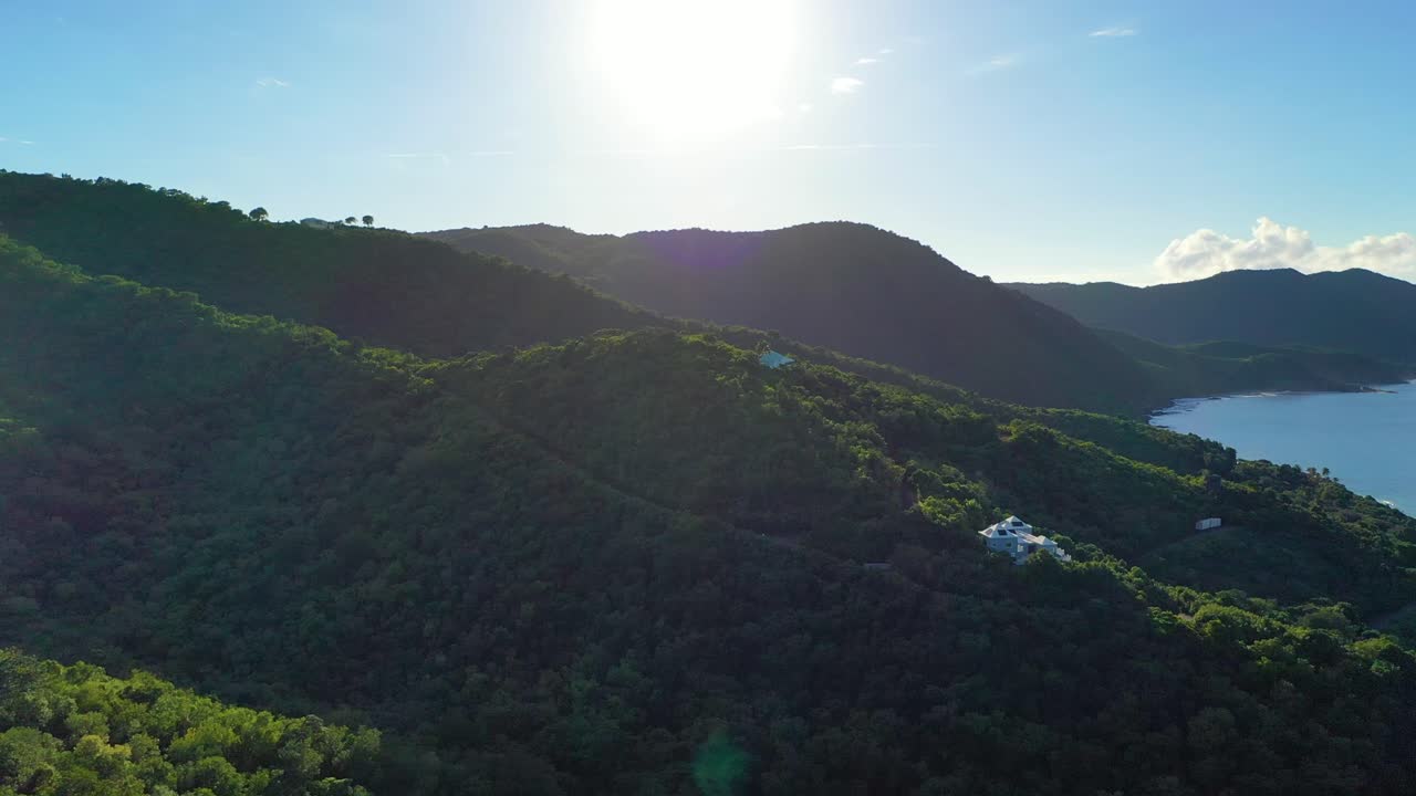 Just a few private luxury villas peek through the dense tropical forest near the Caribbean Sea in St. Croix, USVI, captured from above on a bright, peaceful day