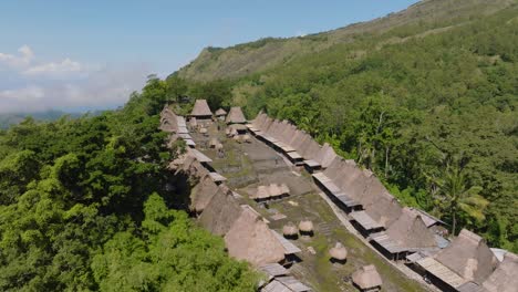 a smooth shot of a small village with huts and a large green forest in indonesia