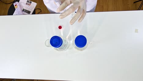 a scientist conducts a potassium permanganate reduction experiment using clear containers on a white table under bright lighting