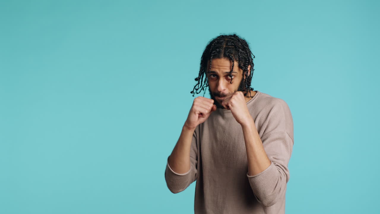 Man throwing punches, holding defensive guard, studio background