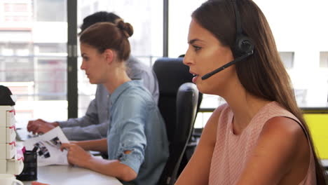 Young-woman-wearing-headset-using-computer-in-office