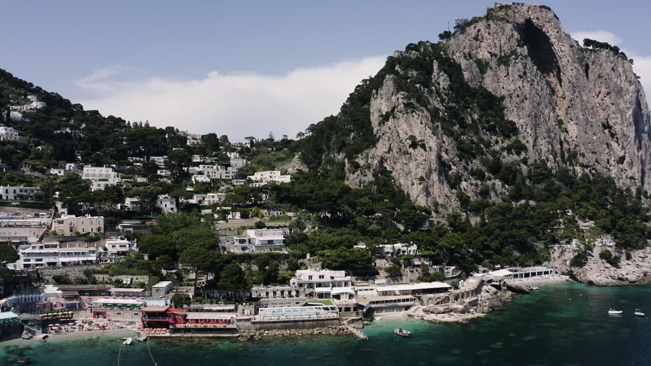 Wide drone shot of Capri, Italy's tourist-focused shoreline