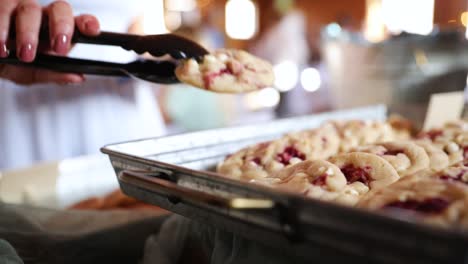 persona que usa pinzas para recoger deliciosas galletas de la bandeja - primer plano