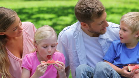 Family-sitting-together-while-eating-slices-of-watermelon